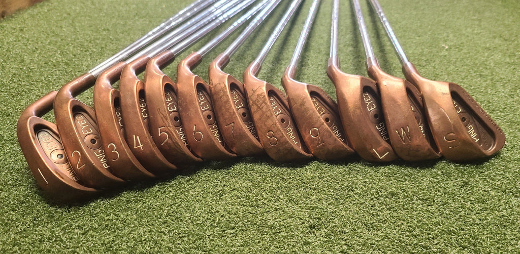 Set of golf clubs with brown heads on a green grass background