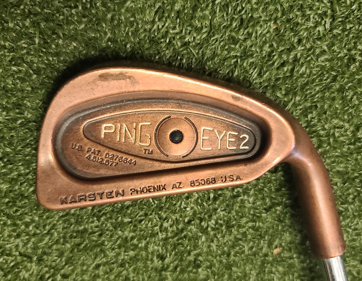 Golf club head with 'Ping' branding on a green grass background